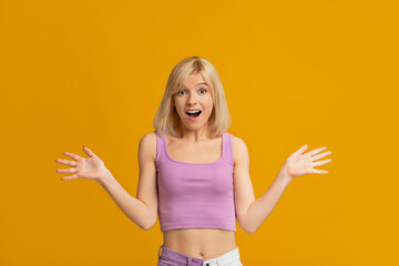 Fototapeta Joyful millennial woman screaming in excitement holding hands near face posing on yellow background in studio. obraz