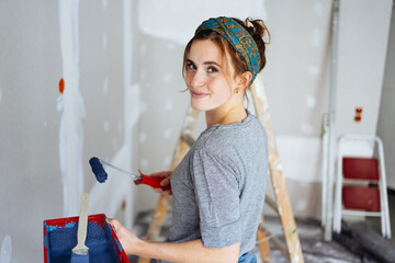Happy young woman decorating the walls of her apartment