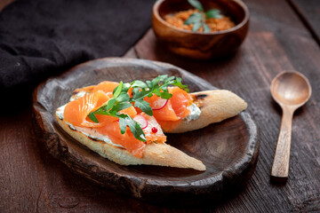 Bruschetta with salmon, cottage cheese and arugula on a white baguette. Breakfast appetizer, salmon sandwich