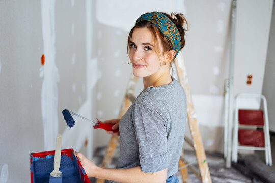 Happy young woman decorating the walls of her apartment