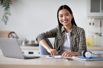 Cheerful asian lady student doing homework at home