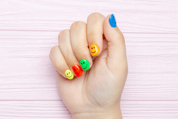 Female hand with multicolored manicure closeup. Manicure with smile emoji	