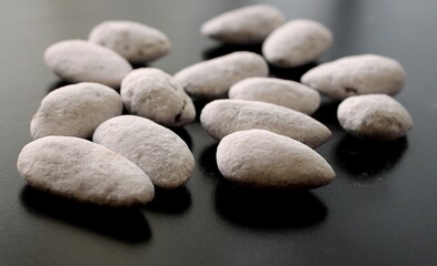 Almond candies on black background, sugared almonds, sweet nuts