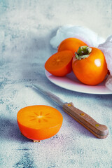 Ripe orange persimmon fruit  on white marble background. Selective focus. Copy space for text.