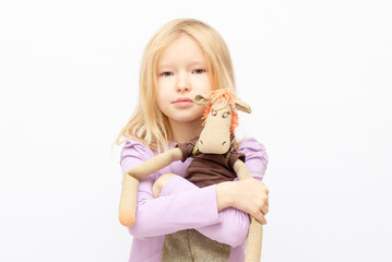 Portrait of beautiful caucasian little girl hugging a toy horse on white background with copy space