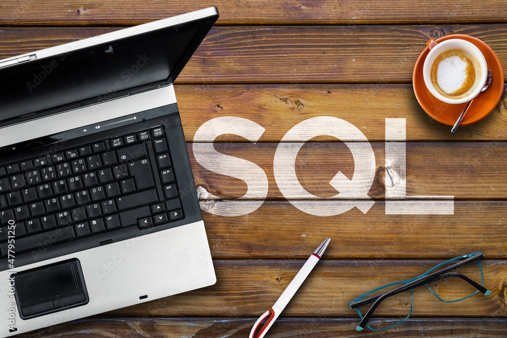 Poster sql programming language. word sql on wooden desk and laptop