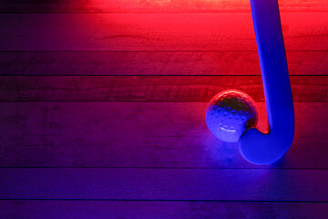 Field hockey and ball on hardwood court floor with neon lighting. Blue neon banner. Horizontal...