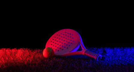 Beach and padel racket and ball on  grass court with neon lighting. Blue neon banner. Horizontal...