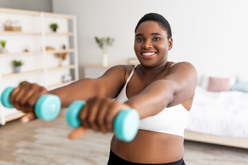 Domestic weightloss training. Positive curvy black woman doing exercises with dumbbells, strengthening her body at home