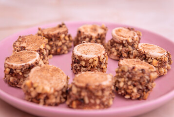Sarah Bernhardt cake with crushed nuts, on a pink plate