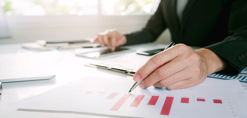 businessman working at office with document on his desk, doing planning analyzing the financial report, business plan investment, finance analysis concept.Using calculator and tablet.