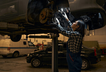 Qualified repair shop technician checking and fixing a car