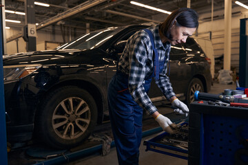 Fototapeta na wymiar Competent female mechanic is searching her toolbox