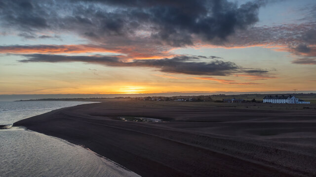 An aerial view of the sun setting over the coast at Shingle Street in Suffolk, UK
