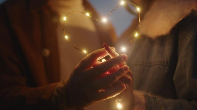 Giovane coppia di ragazzo e ragazza si bacia con striscia di luci led al tramonto