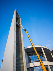 Cleaner workers using a cherry picker to clean a facade of a contemporary office building. 