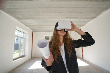 Woman designer with drawings using VR goggles indoors
