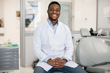 Fototapeta Dental Services. Professional Black Male Stomatologist Posing At Workplace In Clinic Interior obraz