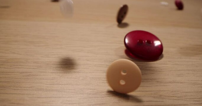 Closeup of different colorful sewing buttons falling on a wooden table. Fashion concept