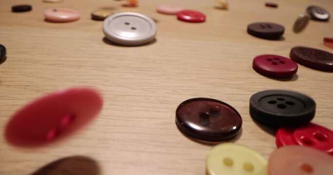 Closeup of different colorful sewing buttons falling on a wooden table. Fashion concept