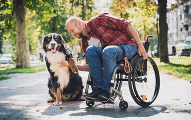 Happy young man with a physical disability who uses wheelchair with his dog.