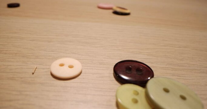 Closeup of different colorful sewing buttons falling on a wooden table. Fashion concept