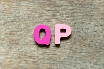 Color alphabet letter in word QP (Abbreviation of Quality procedure) on wood background