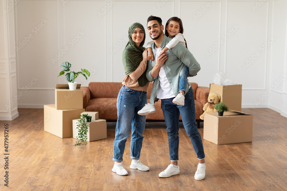 Wall mural happy muslim family looking at camera, posing on moving day