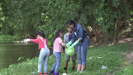 Group of asian kids and teacher school volunteer charity environment under tree near river water. volunteer charity to green recycling bag cleaning park together at ratchaburi thailand.