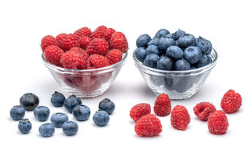 Fresh raspberries and blueberries in glass bowls isolated on white background. Berries in bowl.