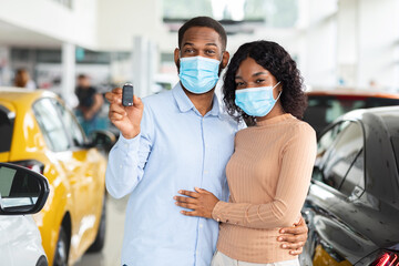 Fototapeta na wymiar Young African American Spouses In Medical Masks Demonstrating Car Key At Camera