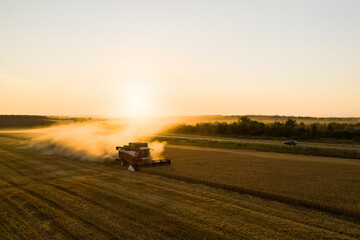 Combine harvester on the field at sunset. Aerial view	