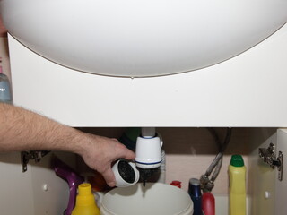 Clogged plastic water trap siphon under the sink in the bathroom, plumbing maintenance