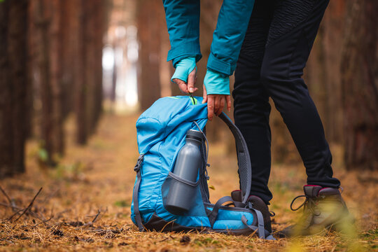 Woman packing backpack after camping in forest and getting ready for hike. Adventure in nature