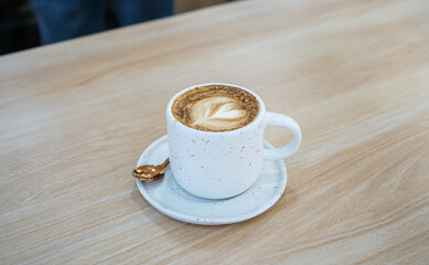 Cup of hot latte coffee on wood deck 