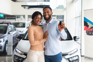 Fototapeta Happy Owners. Cheerful Black Spouses Holding Key Of Their New Car obraz