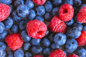 Fresh berry background. Texture of mixture raspberry and blueberry berries close up. Flat lay, top view