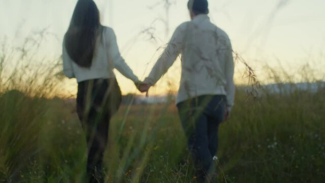 Coppia di ragazzo e ragazza camminano in due mano nella mano in campagna al tramonto