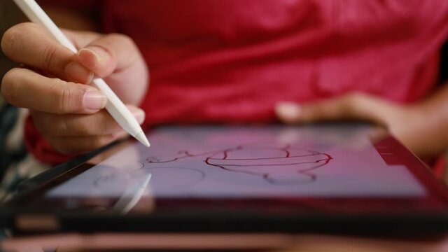 Close-up hand using digital pen drawing on computer tablet