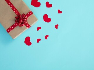 Gift box with red ribbon and bow on blue. Many red hearts. Concept for Valentine's Day or a romantic date or a gift for loved ones. Place for your text.