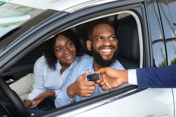 Fototapeta Happy African American Couple Taking Key From Salesman After Buying New Car obraz