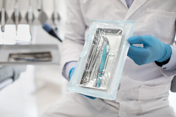 Unrecognizable Dentist Doctor In Uniform Demonstating Sealed Sterilization Pouch With Dental Tools