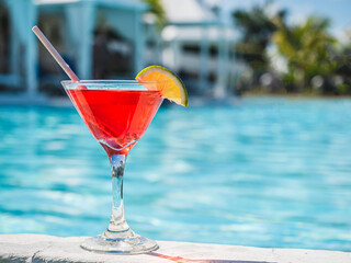 Beautiful glass with a refresh cocktail and a pretty woman on the background of the swim pool. Top view, close-up. Vacation and travel concept. Moments of celebration