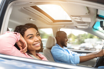 Happy black couple enjoying long drive on a car