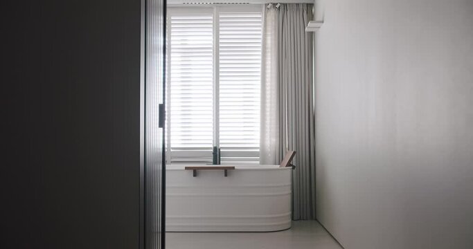 Transparent sliding door opens inside the modern bathroom, minimalist bathtub
