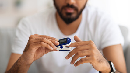 Unrecognizable man using pulse oximeter at home