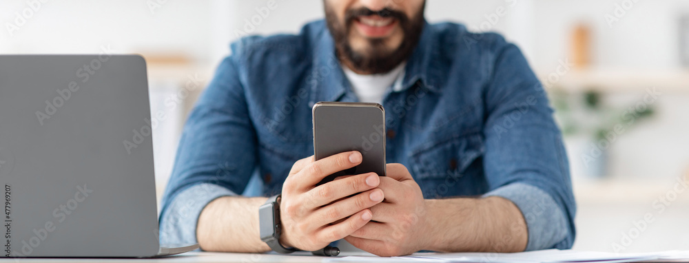 Poster modern technologies for business. unrecognizable guy browsing smartphone and working on laptop, pano
