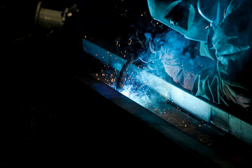 The man welds metal parts from which there are many hot sparks.