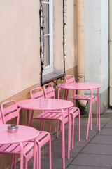 Pink outdoors chairs and tables in the street.