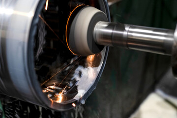 Internal grinding of a part on a CNC machine from which there are a lot of sparks and coolant.